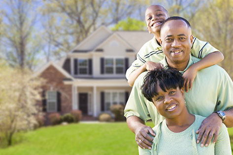 Mom, dad and children smiling in front of new home.