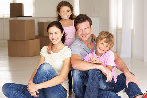 Happy family with moving boxes in the background.